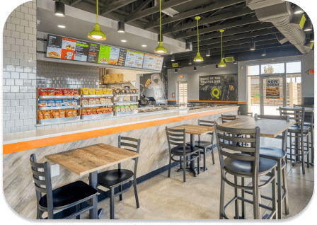 Interior of a modern Quiznos restaurant with counter seating, menu boards, and dining tables.